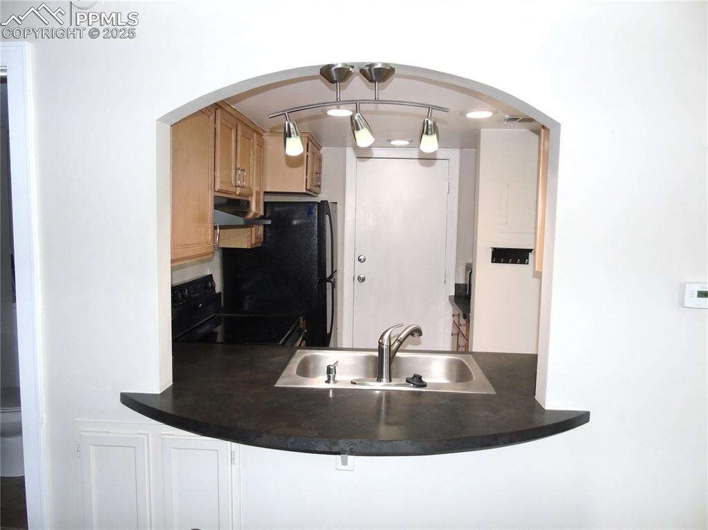 Image 6 of 29: Kitchen with black appliances, pendant lighting, dark countertops, under ca