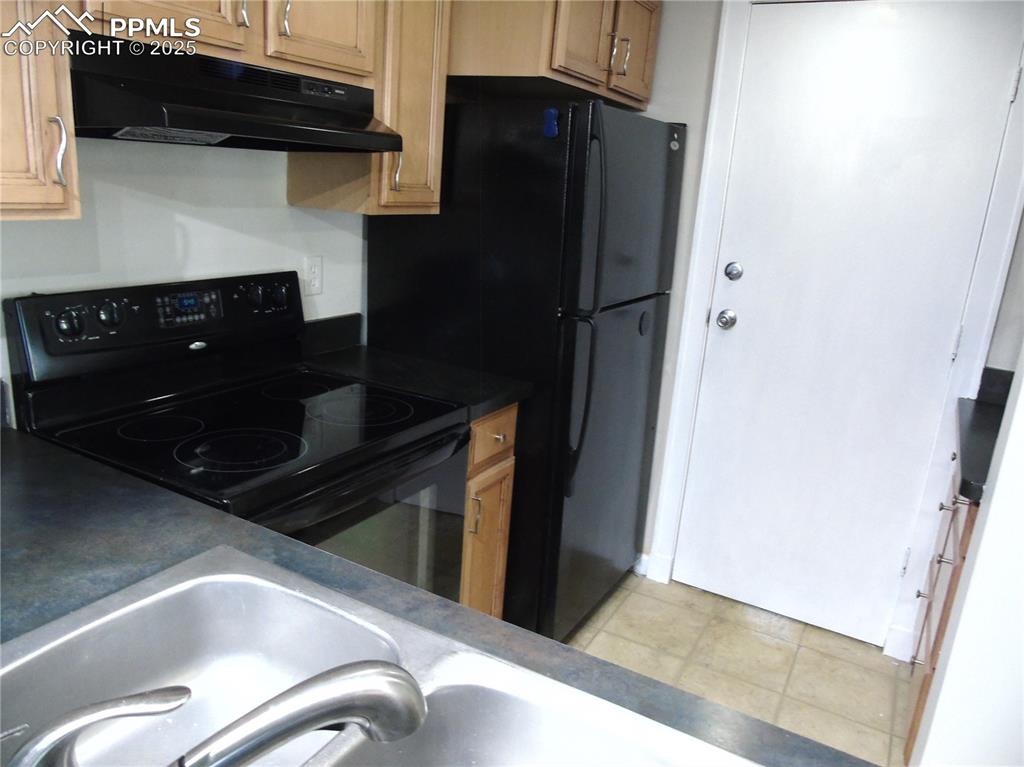 Image 8 of 29: Kitchen with dark countertops, black electric range, under cabinet range ho