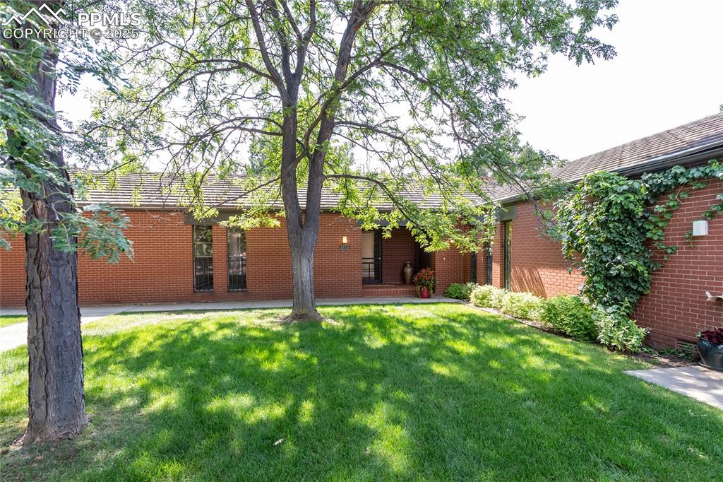 Caption: Front view of property featuring brick siding and a yard