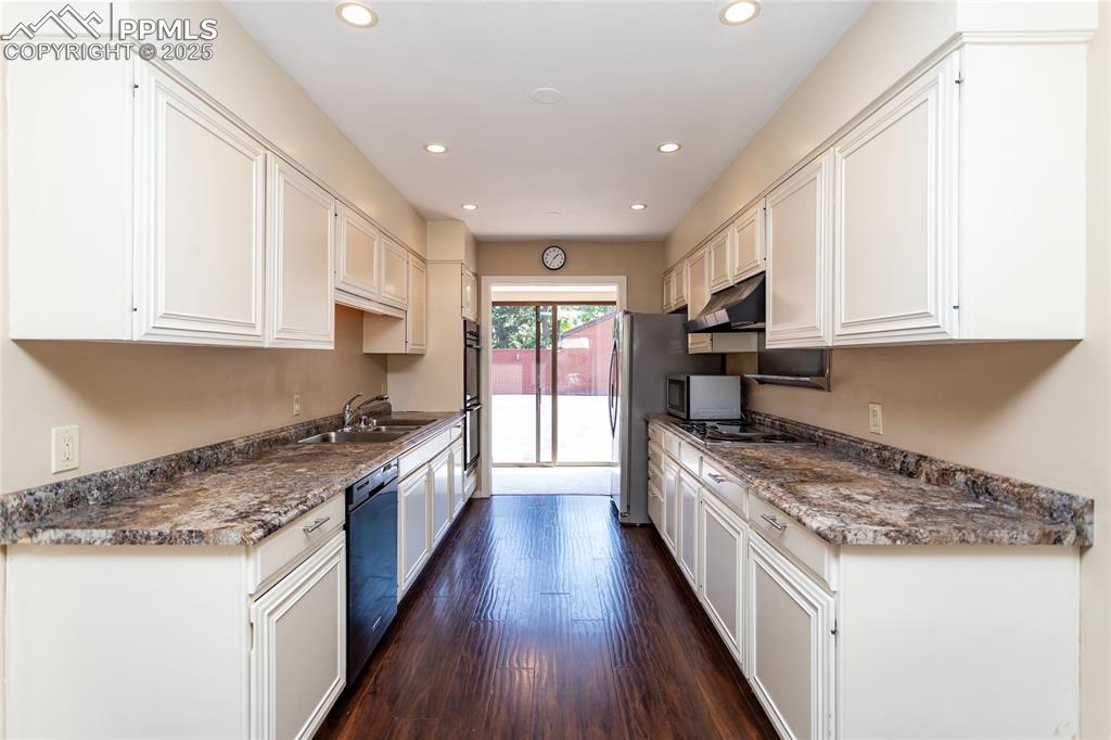 Image 10 of 35: Kitchen featuring recessed lighting, white cabinetry, dark countertops, and