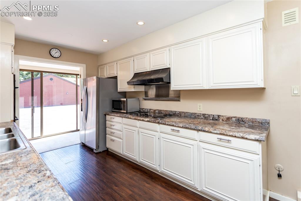 Image 12 of 35: Kitchen featuring dark wood-style flooring, white cabinets, under cabinet r
