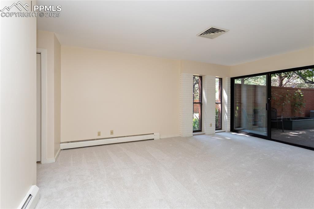 Image 14 of 35: Spare room with a baseboard heating unit and carpet floors