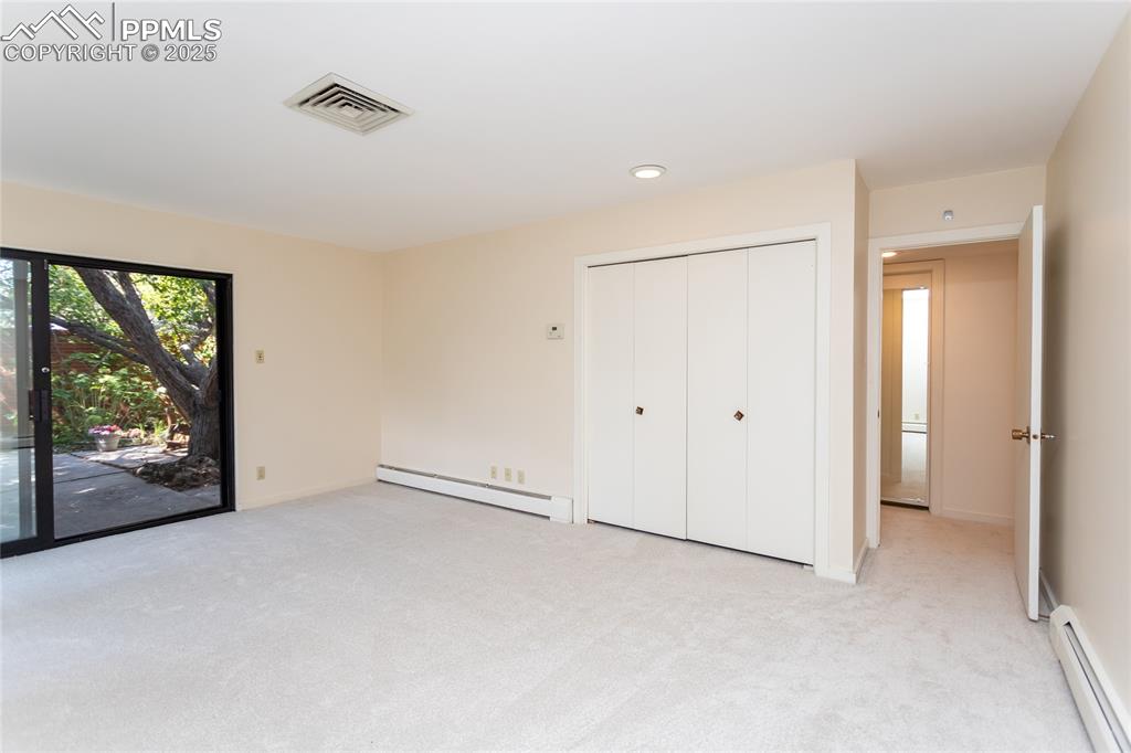 Image 16 of 35: Unfurnished bedroom with baseboard heating, light colored carpet, access to