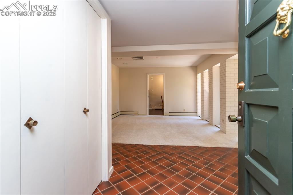 Image 2 of 35: Corridor featuring dark tile patterned floors, dark carpet, and baseboard h