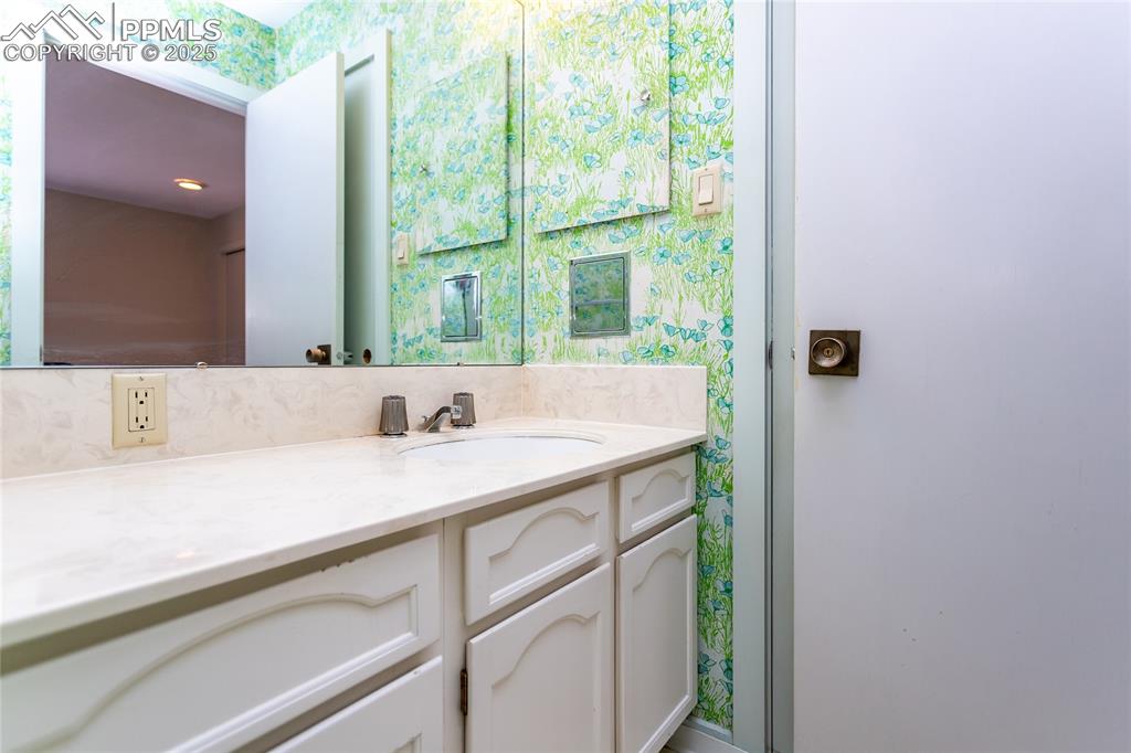 Image 24 of 35: Bathroom with wallpapered walls and vanity