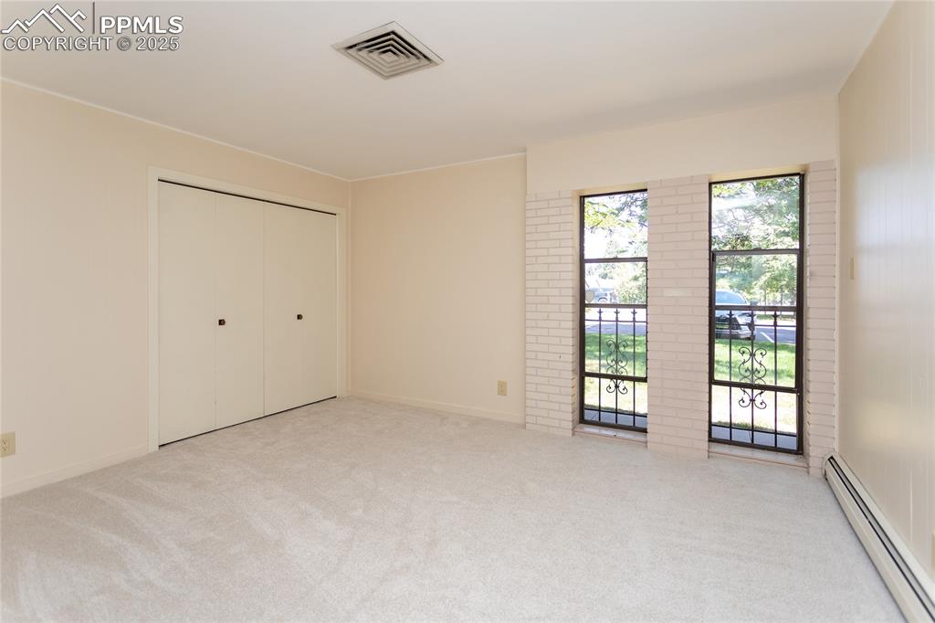 Image 25 of 35: Unfurnished bedroom featuring a baseboard radiator, light carpet, and a clo