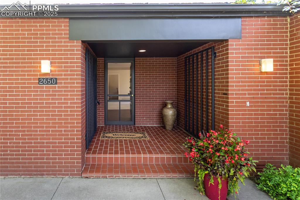 Image 34 of 35: View of exterior entry featuring brick siding and a porch