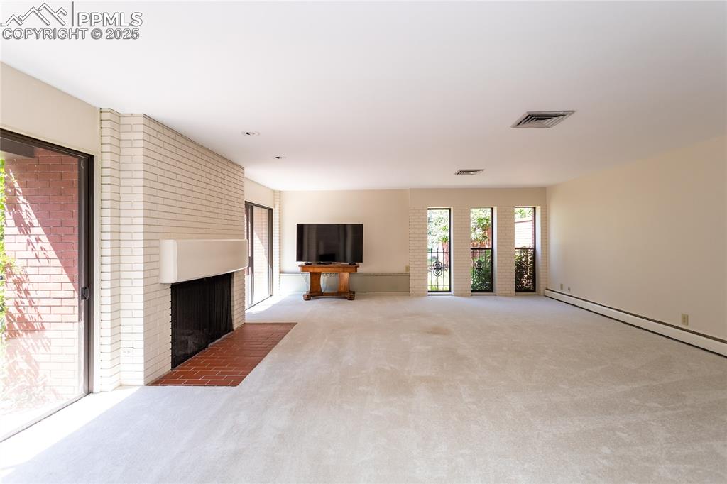 Image 4 of 35: Unfurnished living room with carpet and a brick fireplace