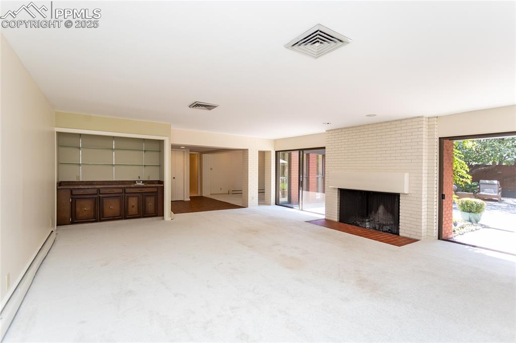 Image 7 of 35: Unfurnished living room with a baseboard radiator, carpet flooring, and a b