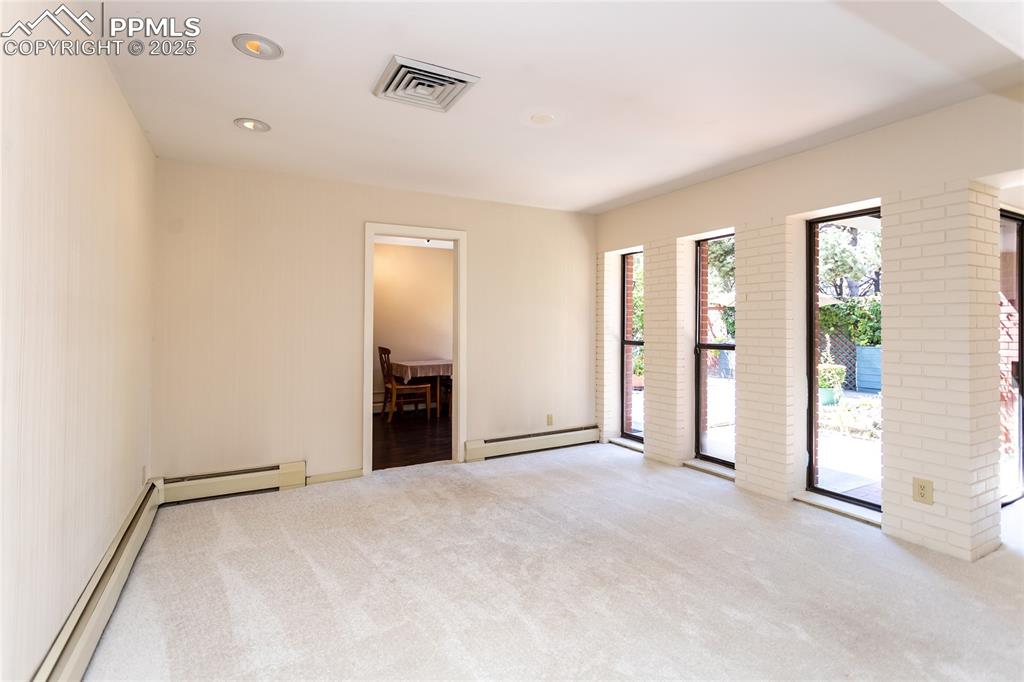 Image 8 of 35: Empty room featuring a baseboard radiator, light colored carpet, and recess