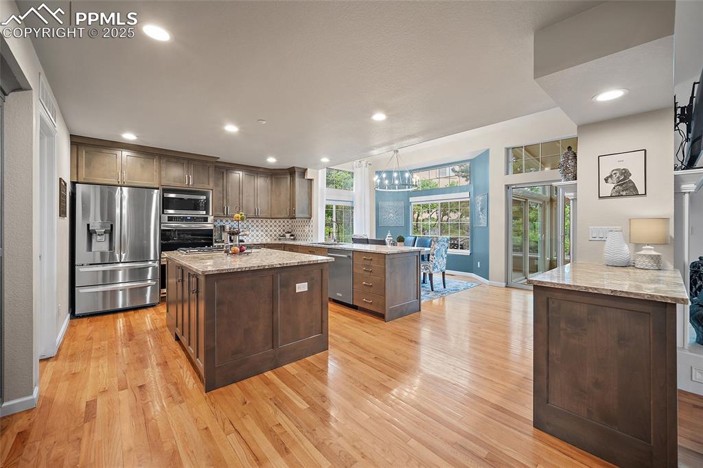 Image 10 of 50: Kitchen featuring stainless steel appliances, a peninsula, wood floors, a k