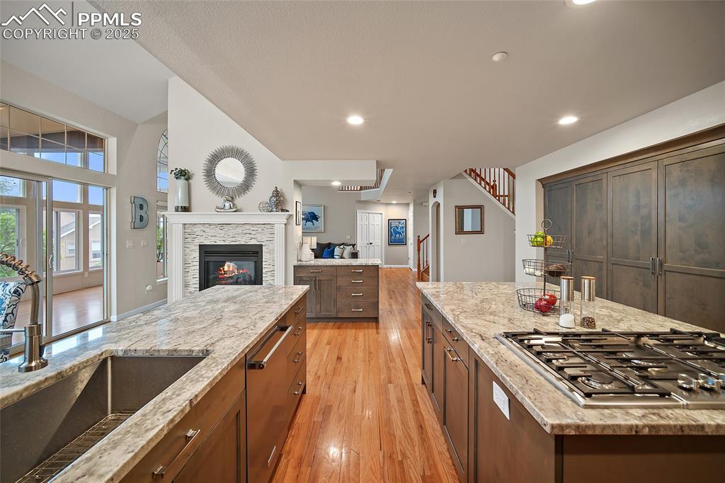 Image 11 of 50: Kitchen featuring stainless steel gas cooktop, light granite counters, wood