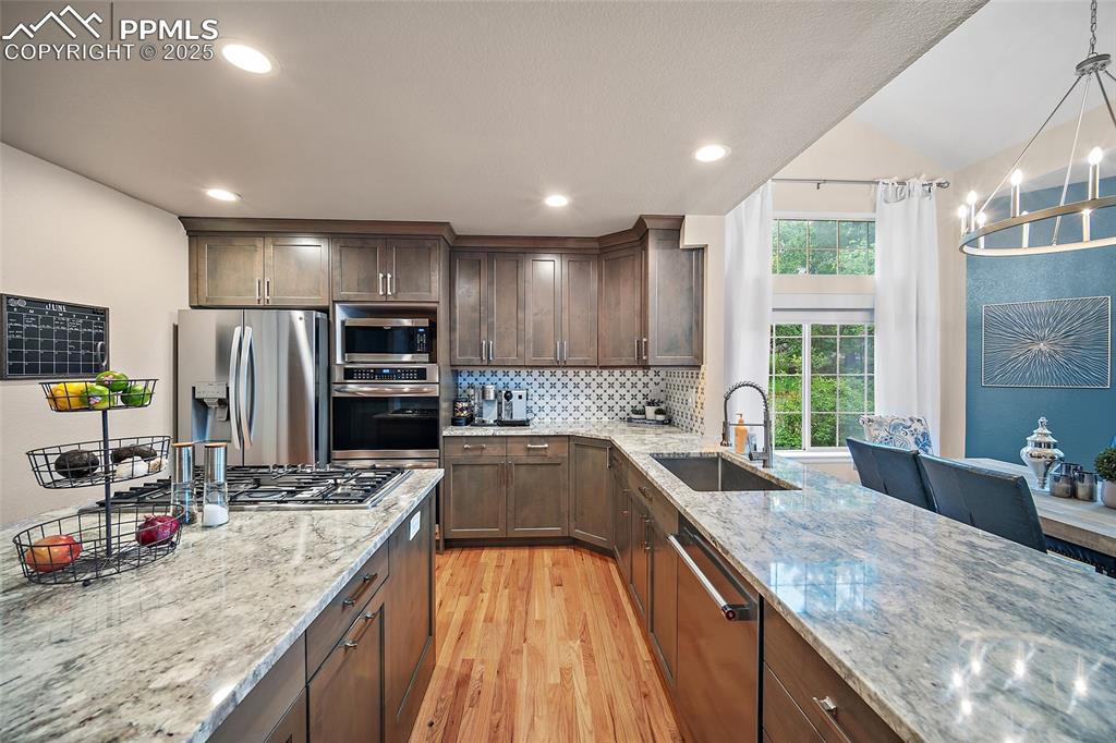 Image 12 of 50: Kitchen featuring stainless steel appliances, a sink, light wood-type floor