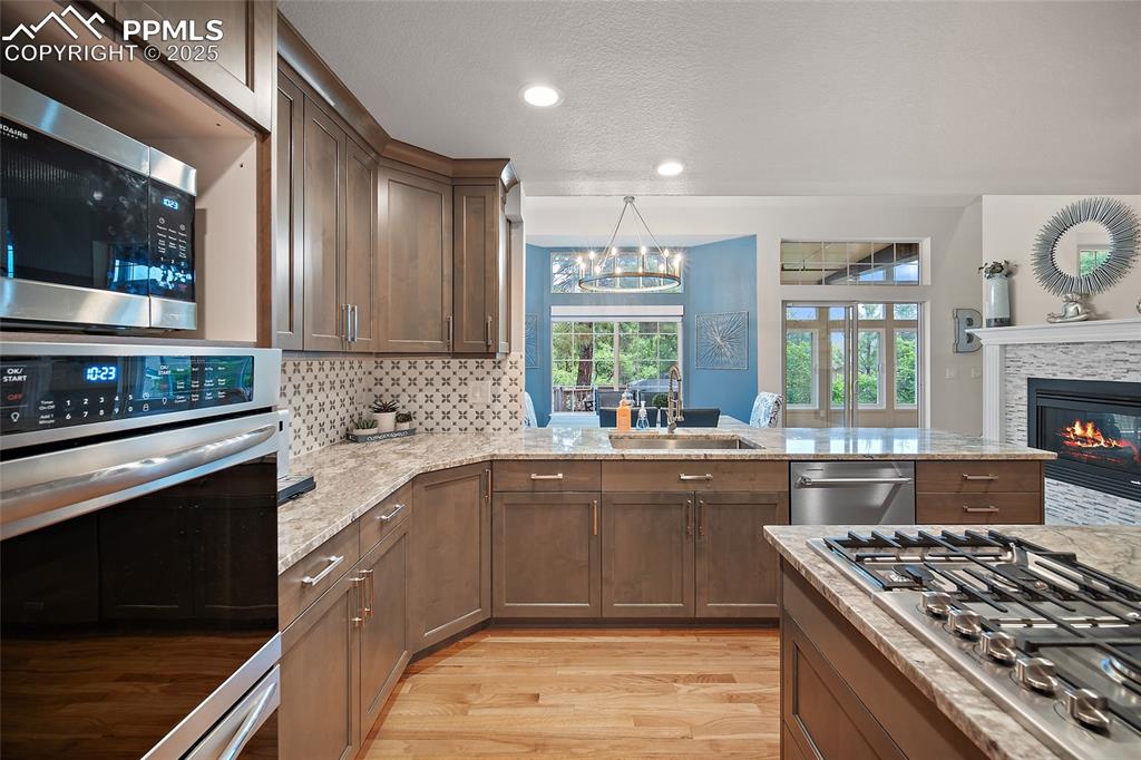 Image 13 of 50: Kitchen featuring stainless steel appliances, a sink, light wood-style floo