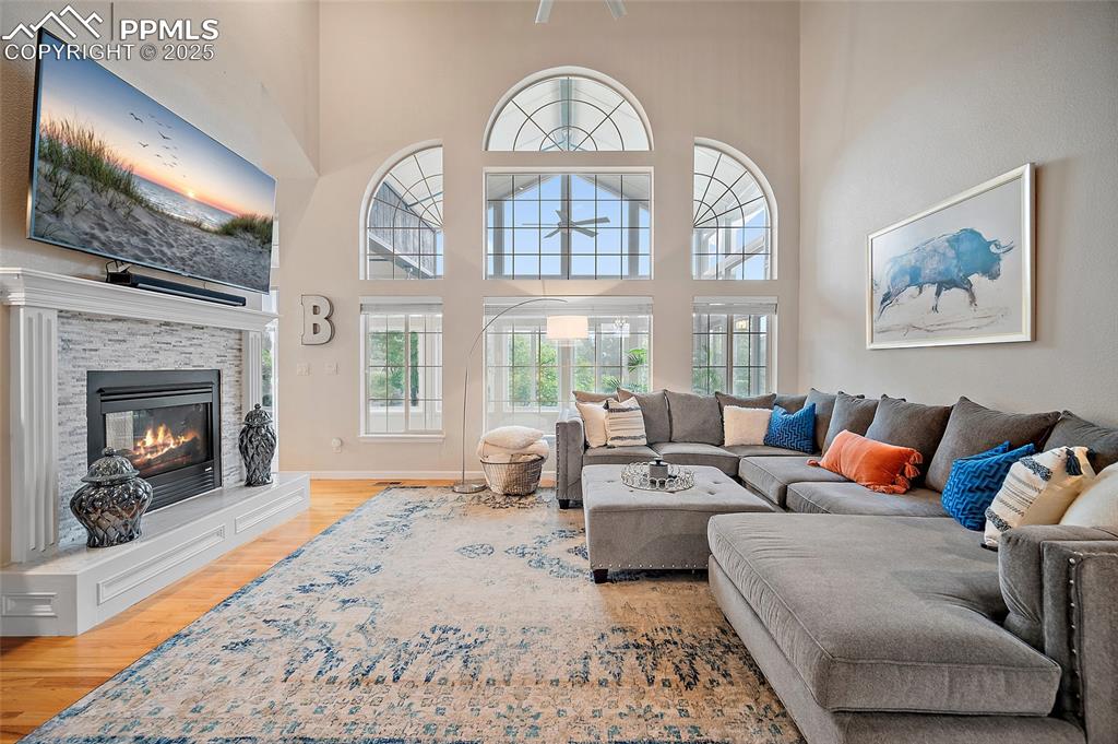 Image 6 of 50: Living room with wood floors, vaulted ceilings, gorgeous windows, and a gas