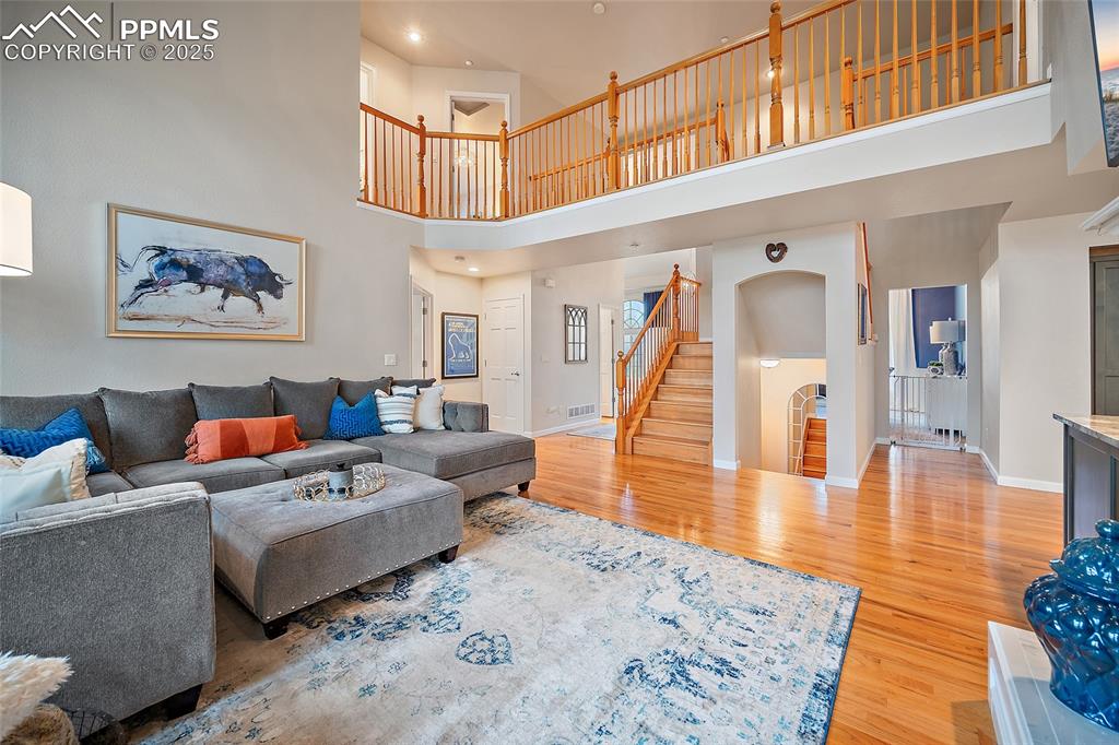 Image 7 of 50: Living room with wood floors, vaulted ceilings, gorgeous windows, and a gas