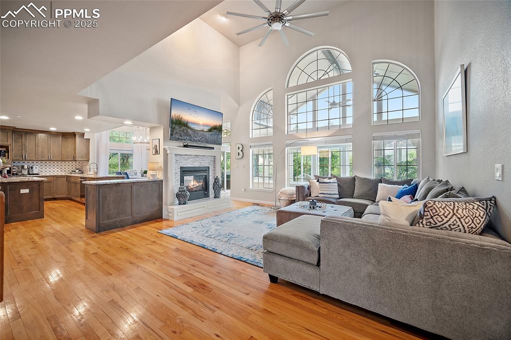 Image 8 of 50: Living room with wood floors, vaulted ceilings, gorgeous windows, and a gas