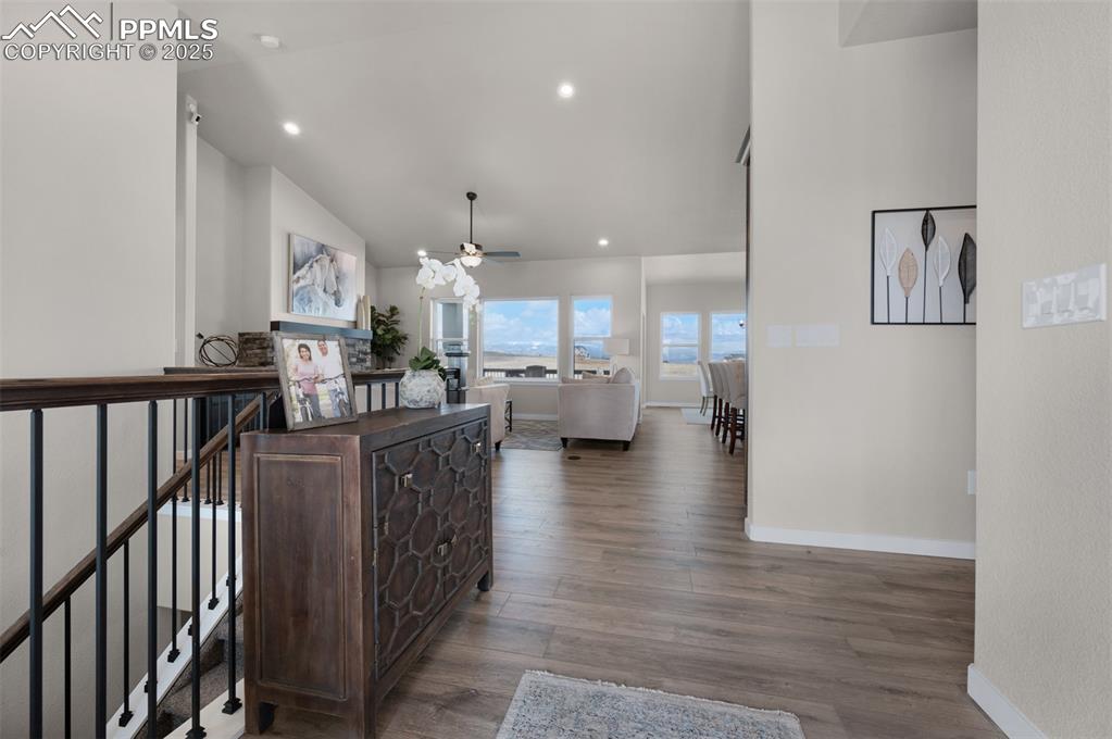 Image 18 of 36: Hall with baseboards, recessed lighting, wood finished floors, and high vau