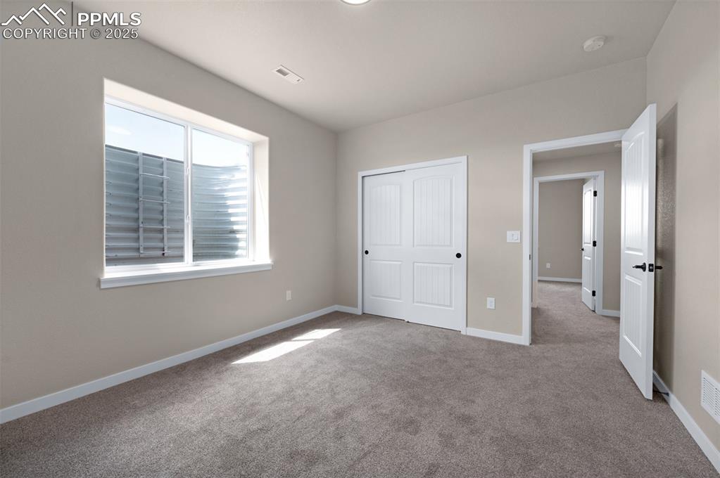 Image 36 of 36: Unfurnished bedroom with carpet flooring, baseboards, visible vents, and a