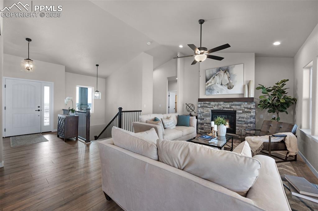 Image 6 of 36: Living room featuring a stone fireplace, vaulted ceiling, dark wood-style f
