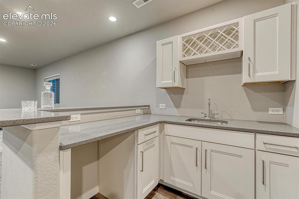 Image 25 of 43: wet bar with quartz counters and custom cabinetry