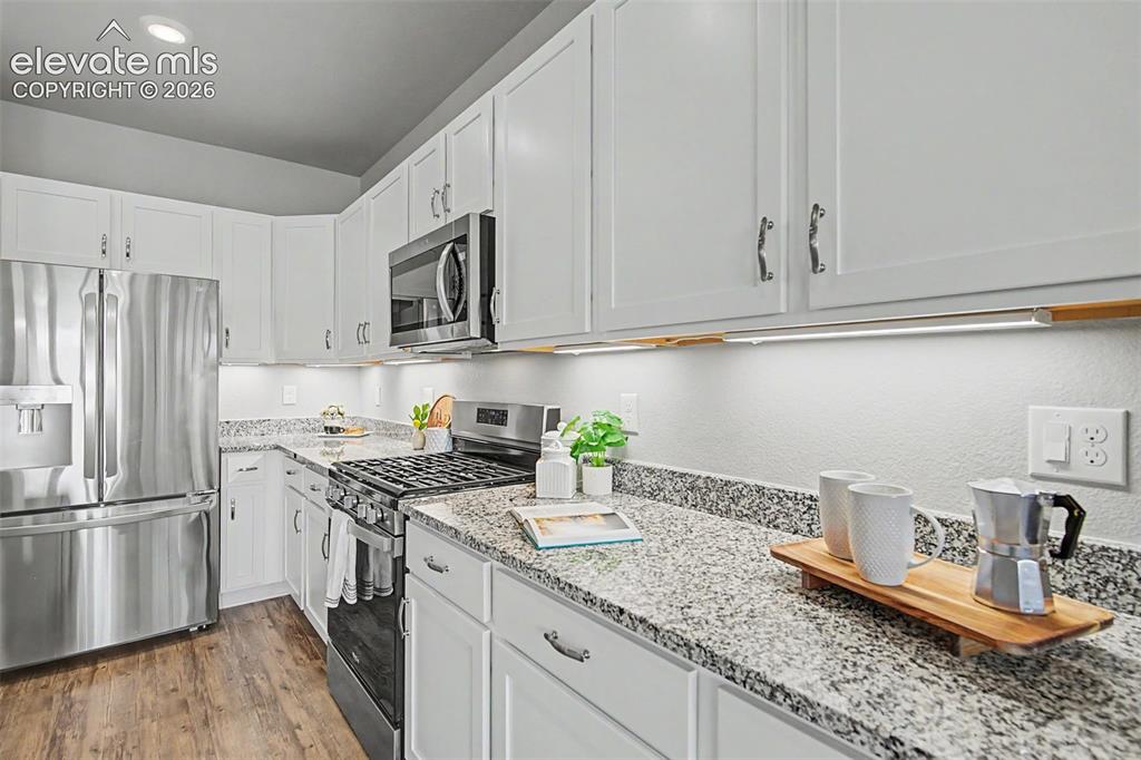 Image 10 of 45: Contemporary kitchen featuring white cabinetry with silver hardware, speckl