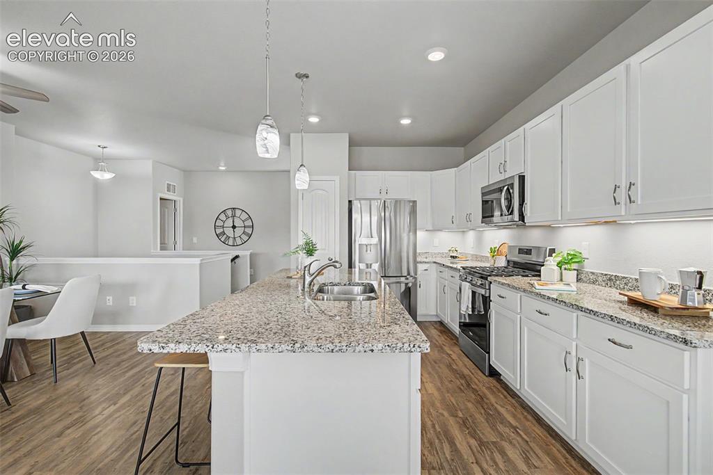 Image 14 of 45: Spacious kitchen featuring an island with a stainless steel sink, under-cab
