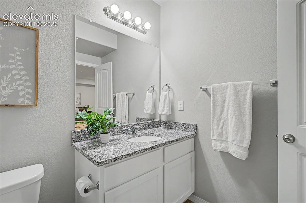 Image 30 of 45: Bathroom vanity featuring a speckled countertop, undermount sink, and chrom