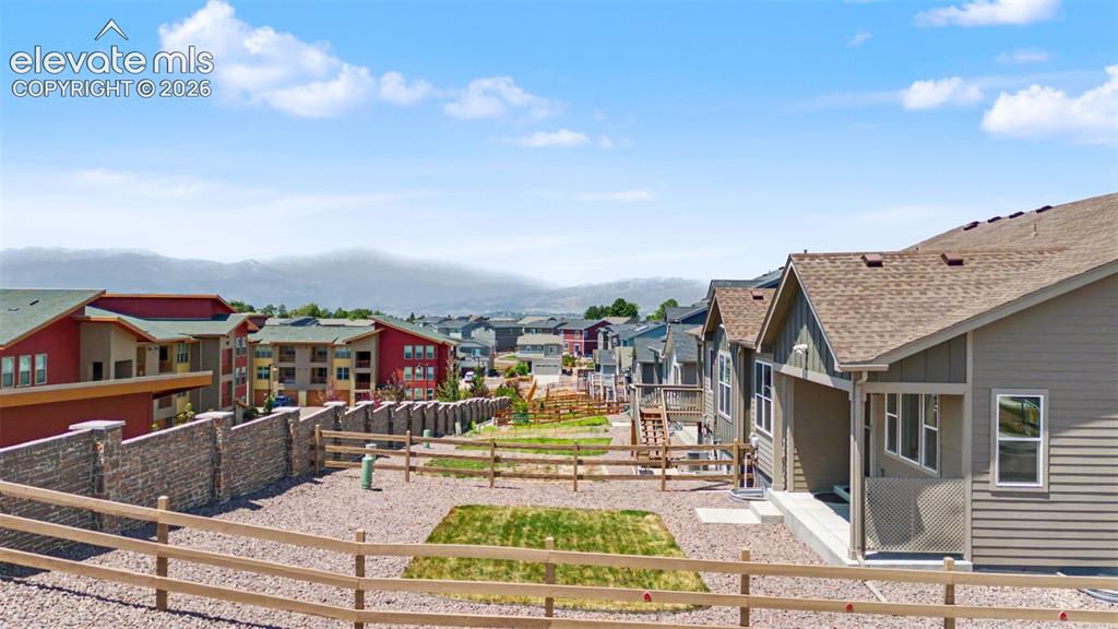 Image 43 of 45: Fenced backyard area featuring gravel and small lawn sections, with a cover