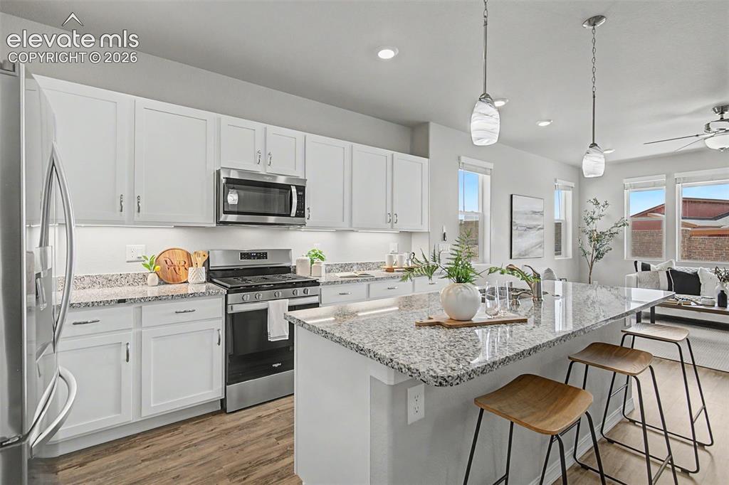 Image 6 of 45: Kitchen featuring an expansive island with a granite-style countertop, whit