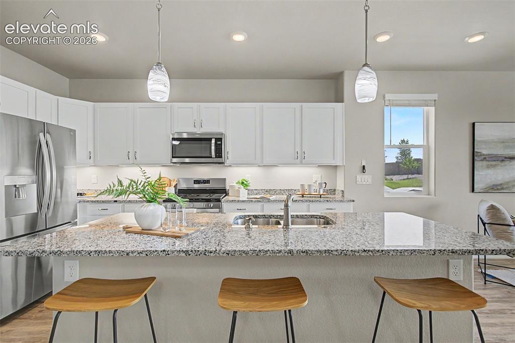 Image 7 of 45: Kitchen featuring white cabinetry, stainless steel appliances, and stone co