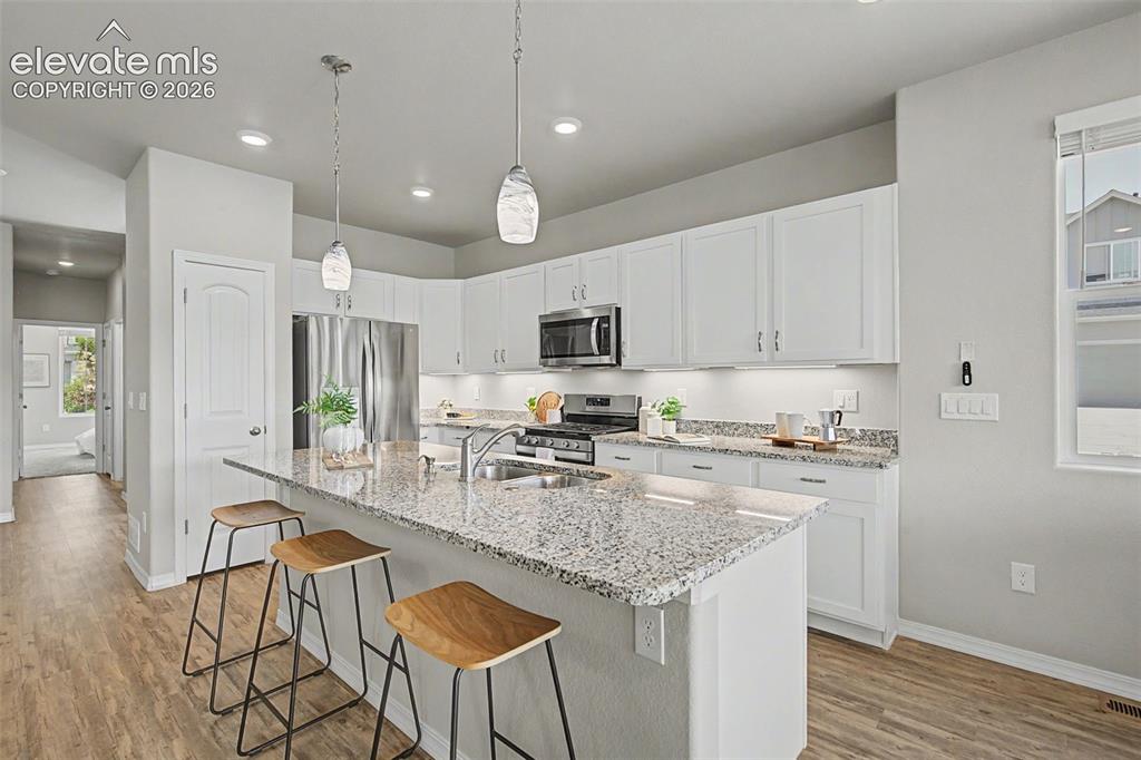 Image 8 of 45: Open-concept kitchen featuring white cabinetry, stainless steel appliances,