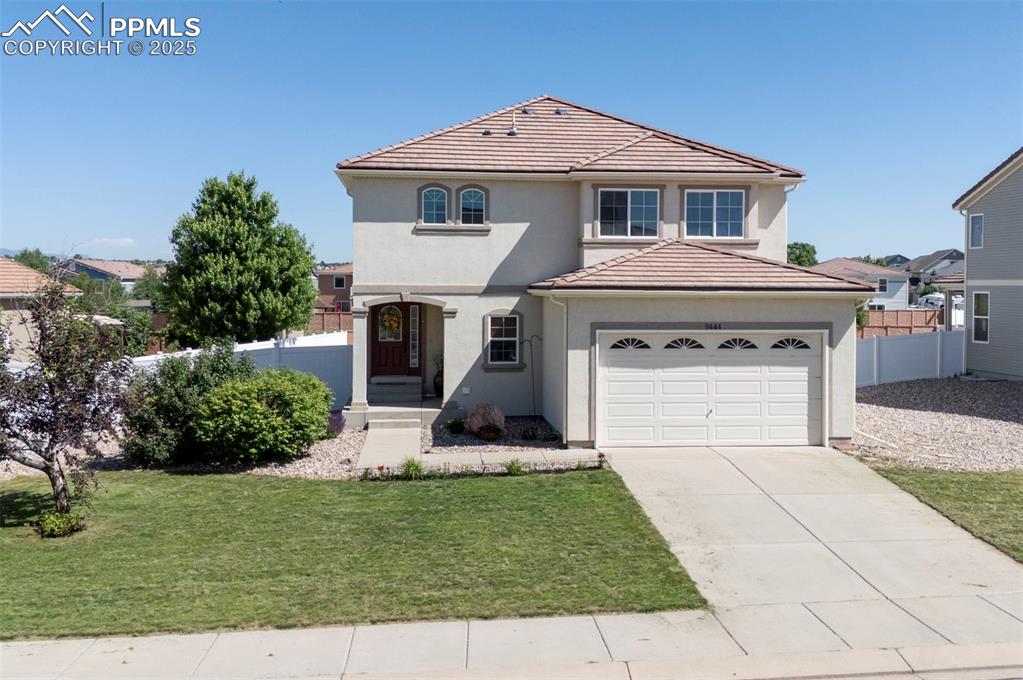 Caption: View of front facade featuring stucco siding, a tile roof, and driveway