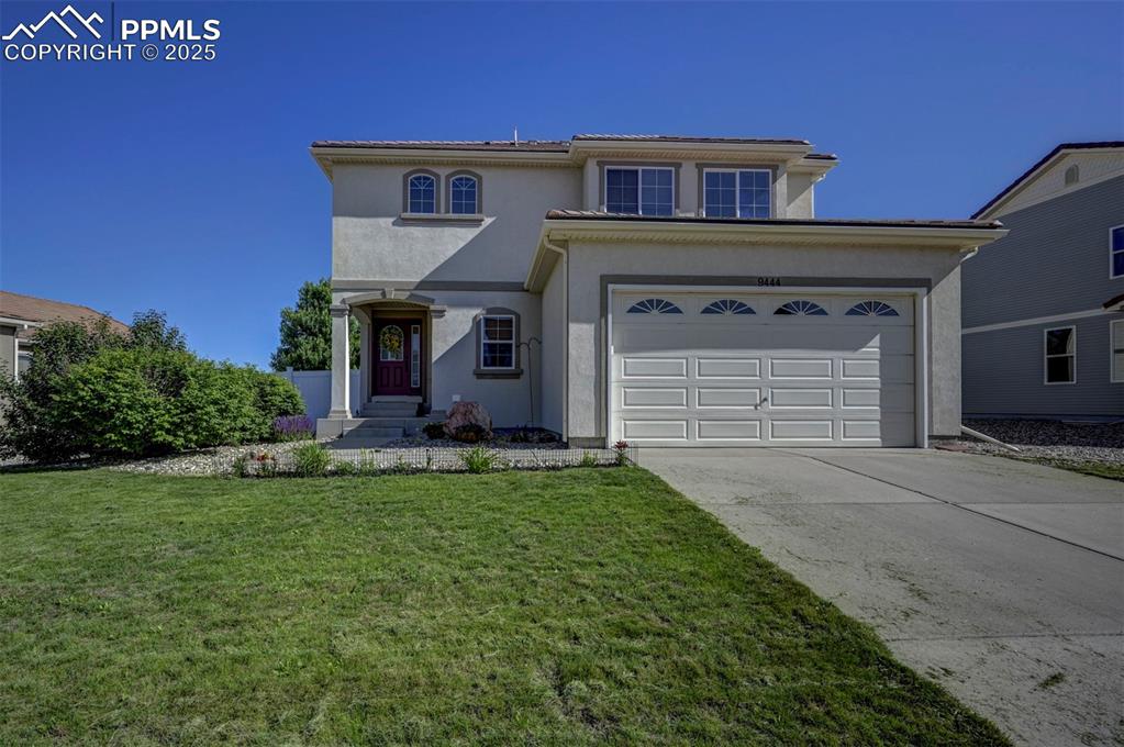 Image 11 of 50: View of front of house with driveway, stucco siding, a front yard, and a ga