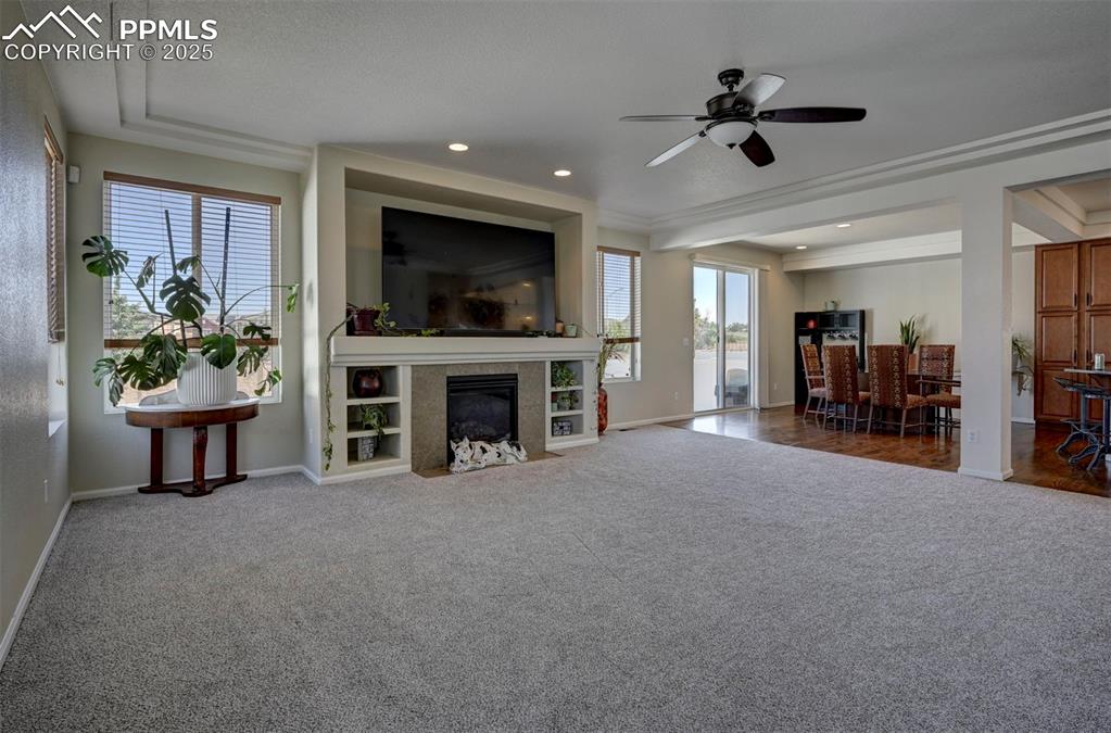 Image 19 of 50: Living room with carpet flooring, a ceiling fan, a fireplace with flush hea