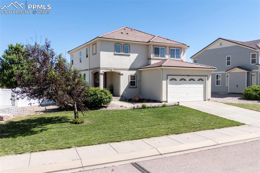 Image 2 of 50: View of front of property featuring driveway, stucco siding, an attached ga