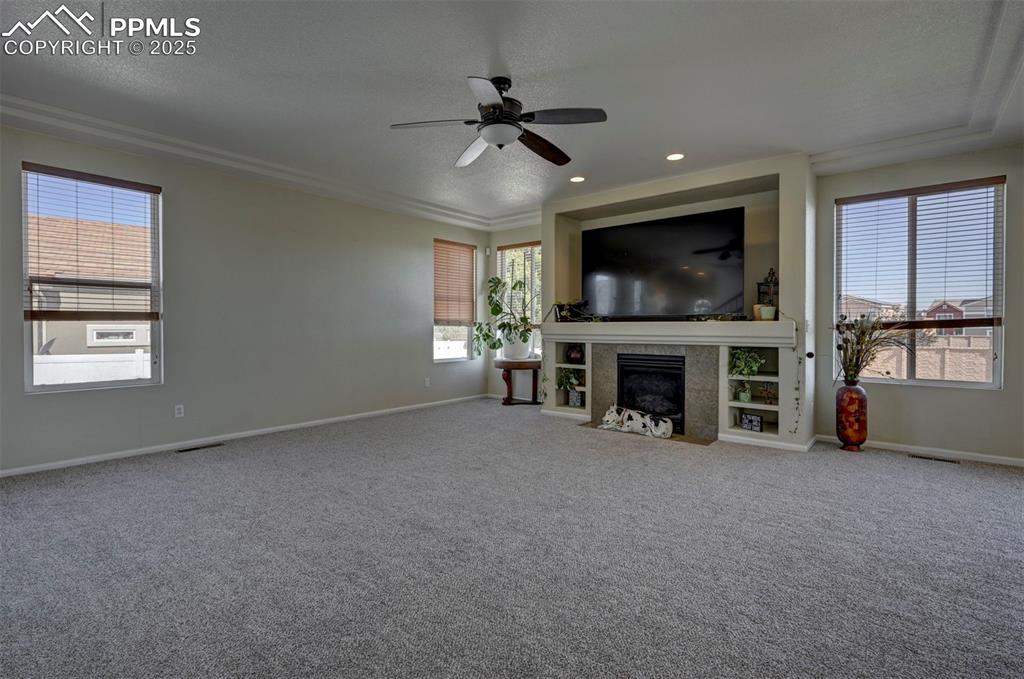 Image 20 of 50: Unfurnished living room with ceiling fan, plenty of natural light, carpet,