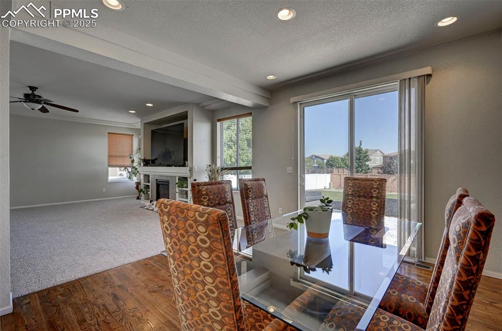 Image 24 of 50: Dining area with wood finished floors, a fireplace with flush hearth, a cei