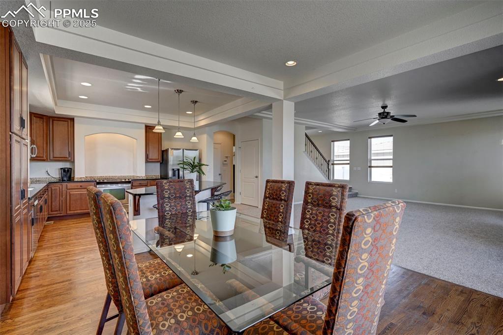 Image 25 of 50: Dining area with arched walkways, light wood-type flooring, a tray ceiling,