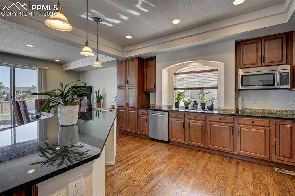 Image 26 of 50: Kitchen featuring appliances with stainless steel finishes, light wood-styl