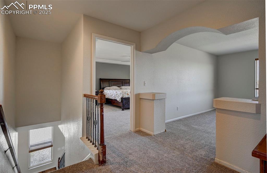 Image 32 of 50: Hallway featuring carpet flooring, an upstairs landing, and arched walkways