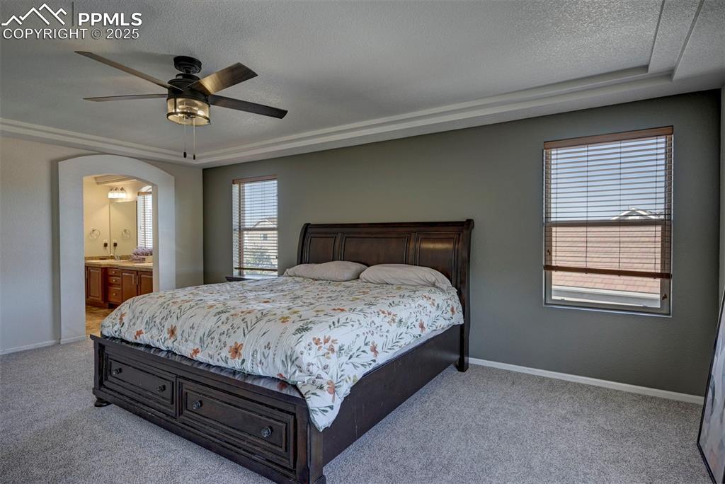 Image 42 of 50: Bedroom with light carpet, arched walkways, a textured ceiling, ensuite bat