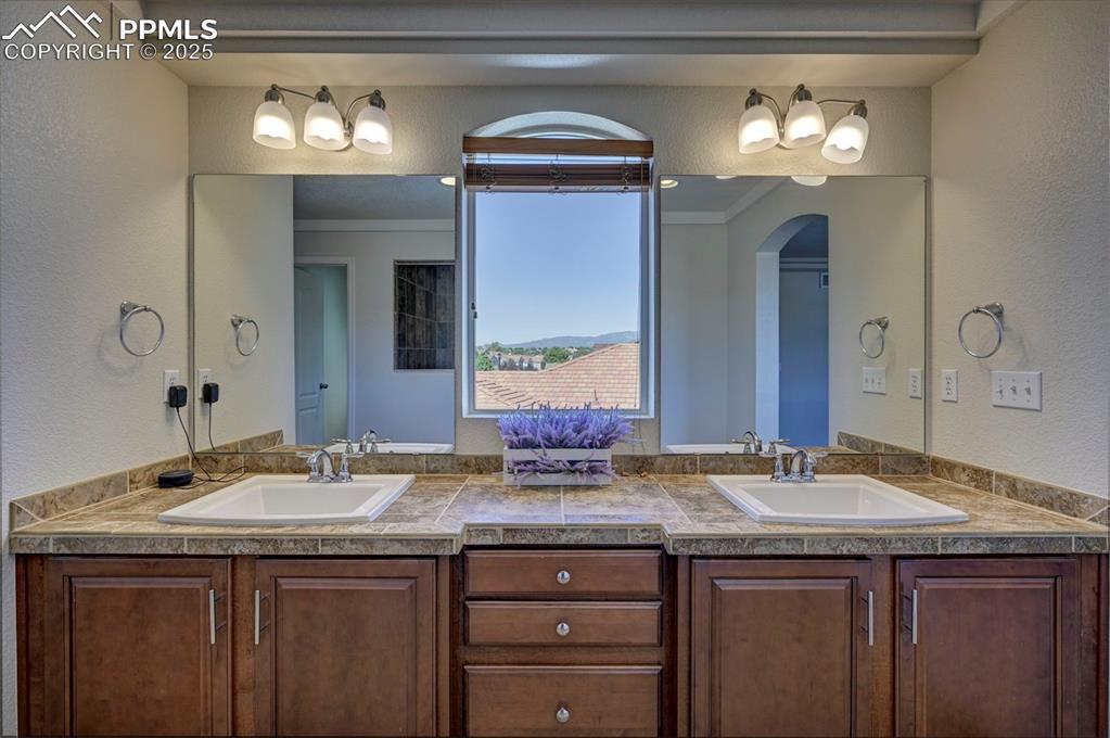 Image 45 of 50: Full bath with double vanity, plenty of natural light, a textured wall, and