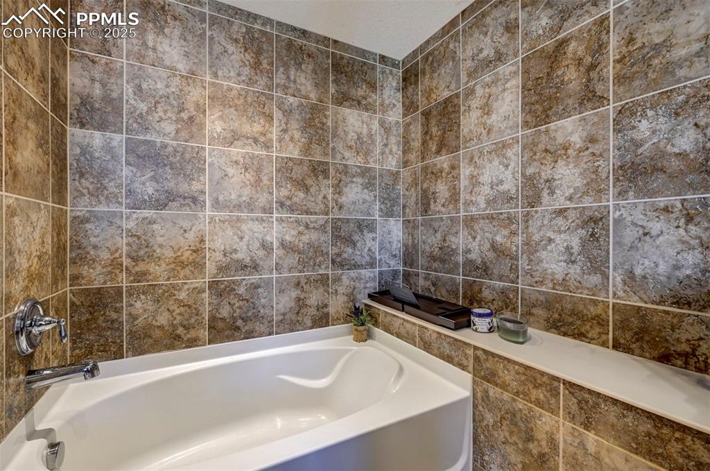 Image 46 of 50: Bathroom with a garden tub and tile walls