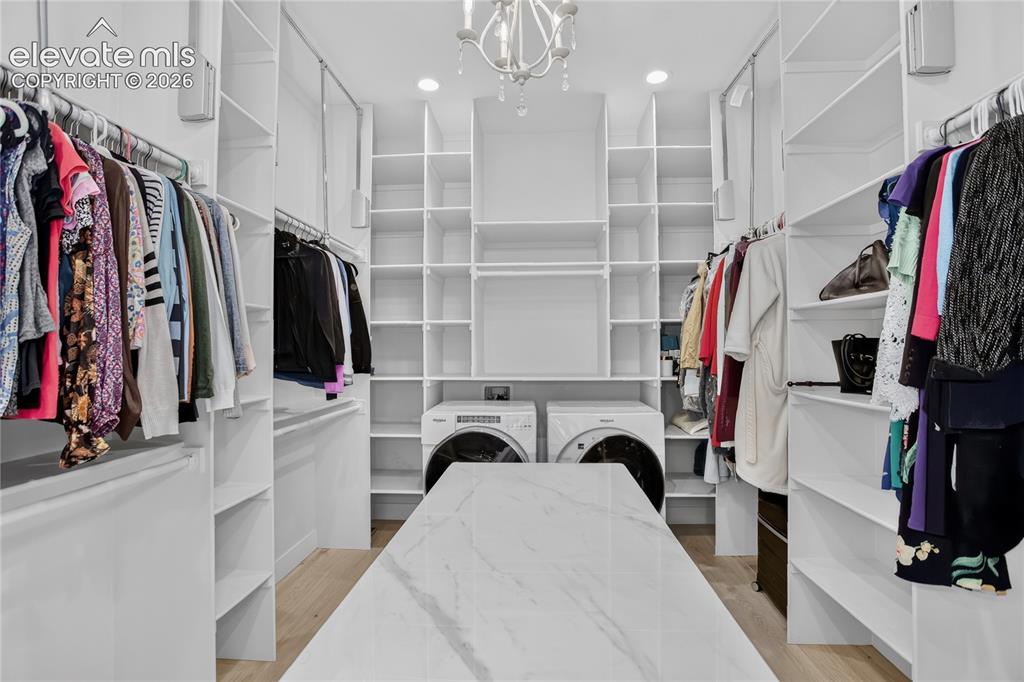 Image 22 of 47: Primary closet - packing island, pull down rods, & dedicated laundry