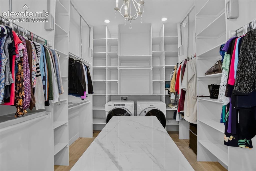 Image 22 of 47: Primary closet - packing island, pull down rods, & dedicated laundry