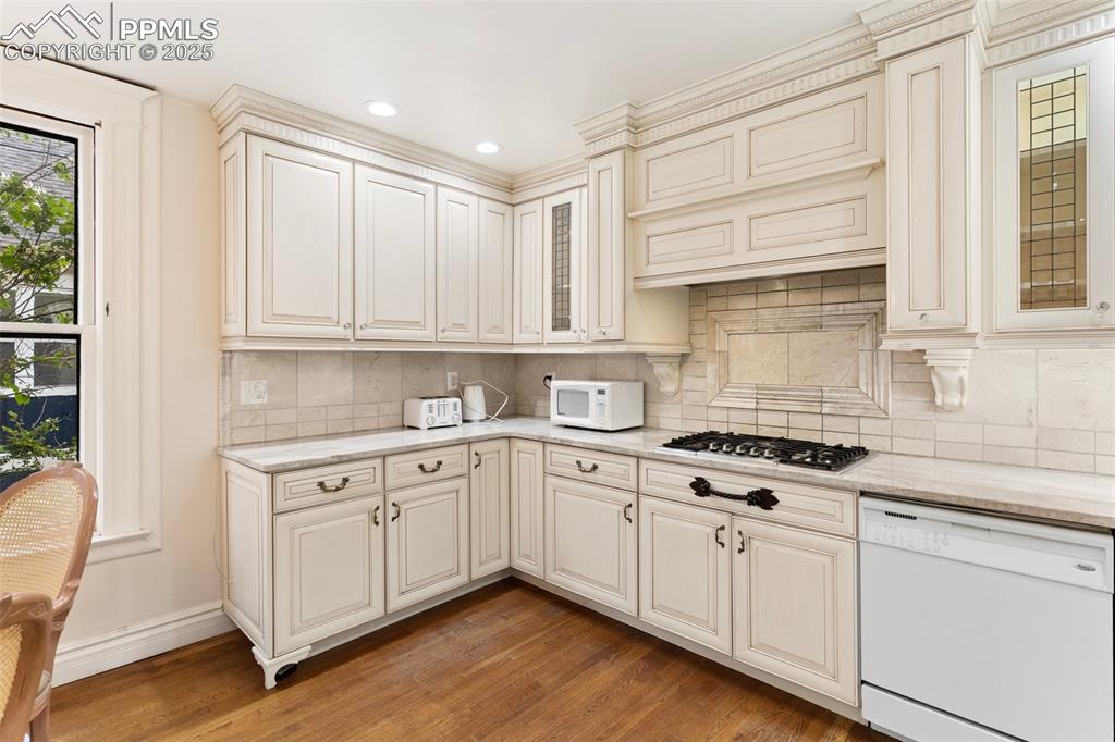 Image 19 of 50: Kitchen featuring white appliances, light wood-style flooring, decorative b
