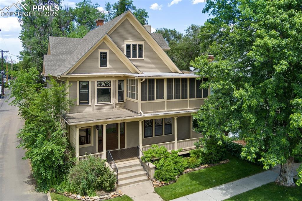 Image 2 of 50: View of front of house featuring a chimney, a porch, a sunroom, a shingled 