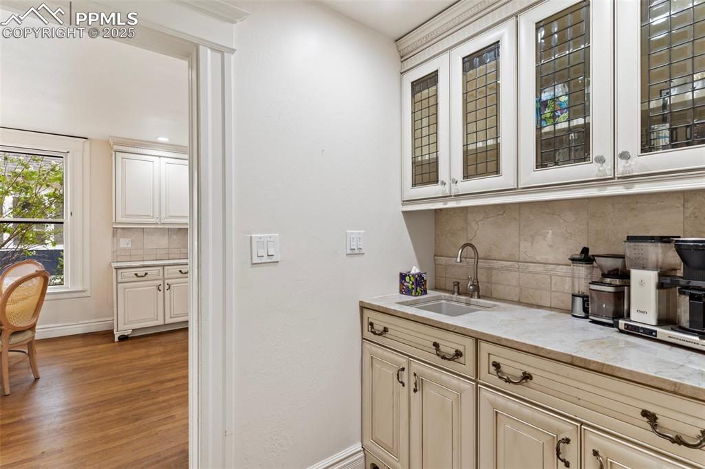 Image 21 of 50: Bar area with decorative backsplash and light wood-type flooring