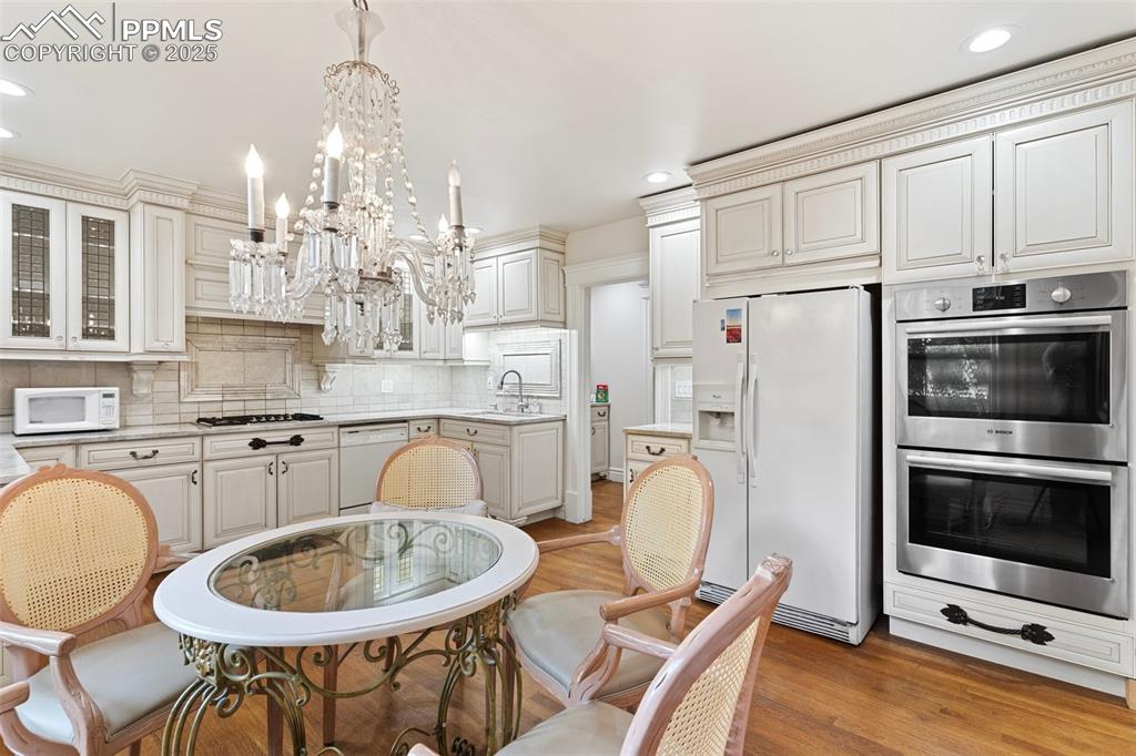 Image 25 of 50: Kitchen with white appliances, a chandelier, light countertops, recessed li